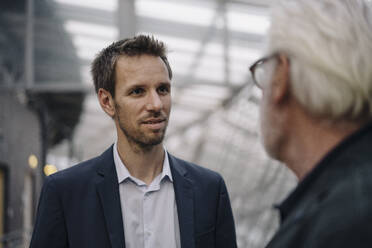 Portrait of businessman looking at senior colleague in office - JOSF03965