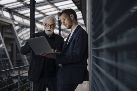 Zwei Geschäftsleute benutzen gemeinsam einen Laptop im Büro, lizenzfreies Stockfoto