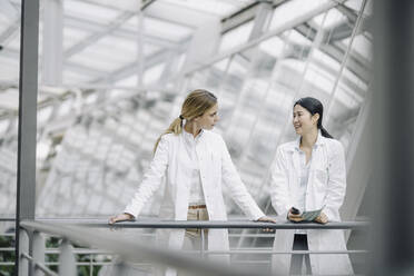 Two female doctors talking in a modern building - JOSF03996