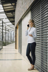 Smiling young businesswoman on the phone in a modern office building - JOSF04014