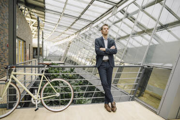 Businessman with bicycle in modern office building - JOSF04028