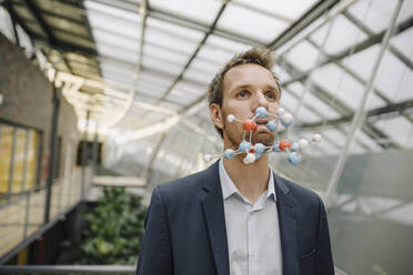 Portrait of businessman with atomic modelin his mouth - JOSF04029