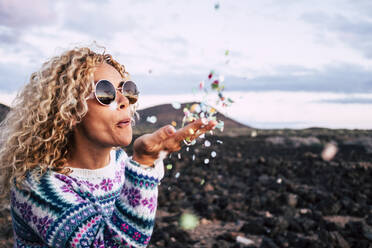 Blond woman blowing confetti in the air, Tenerife, Spain - SIPF02096