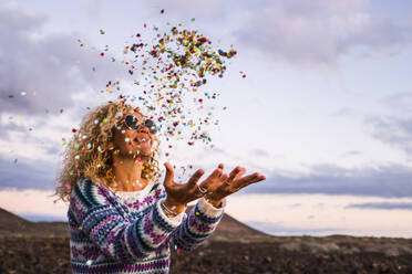 Glückliche blonde Frau wirft Konfetti in die Luft, Teneriffa, Spanien - SIPF02097