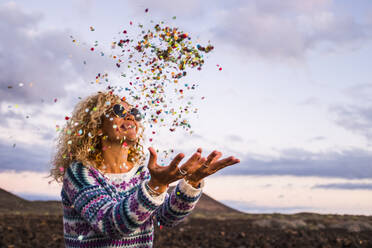 Happy blond woman throwing confetti in the air, Tenerife, Spain - SIPF02097