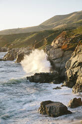 Scenic view of waves breaking on rocks against clear sky - CAVF70020