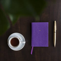 Overhead view of coffee in cup and diary on table - CAVF70025