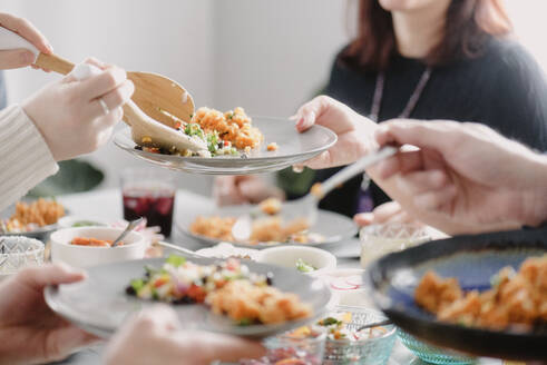 Mittelteil einer Frau beim Mittagessen mit Freunden am Esstisch - CAVF70034