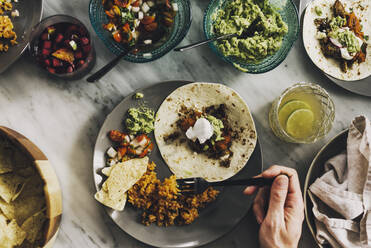 Abgeschnittene Hand eines Mannes beim Mittagessen am Esstisch - CAVF70039