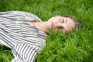 Young woman lying on grass, looking at camera - PESF01737