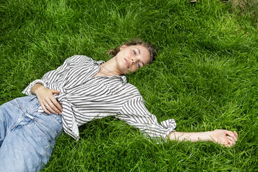 Young woman lying on grass, looking at camera - PESF01738