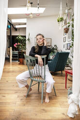 Young woman sitting on chair at home - PESF01753