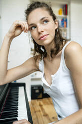 young woman sitting at the piano, smiling - PESF01760