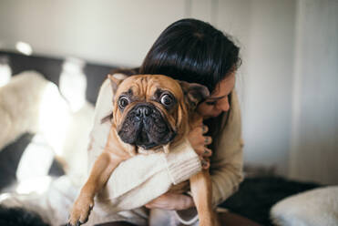 A tattooed woman hugging her cute puppy. Happy moment between pe - CAVF70167