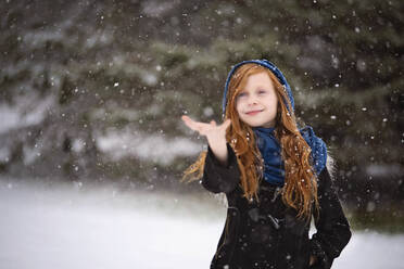 Junges rothaariges Mädchen, das draußen im Schnee spielt - CAVF70183