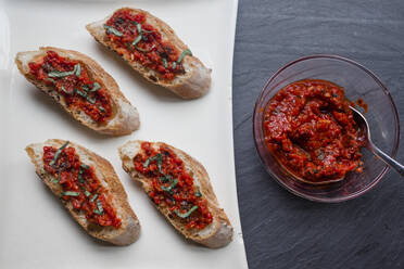 Platte mit Tomaten-Paprika-Bruschetta und frischem Basilikum auf schwarzem Schiefer - CAVF70227