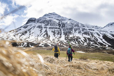 Two backcountry skiers hiking to the snow in Iceland. - CAVF70233