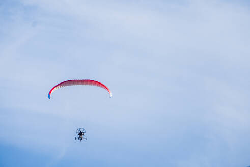 Gleitschirmfliegen mit Wanderer gegen den Himmel - CAVF70297