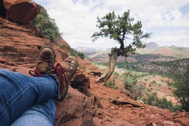 Low section of man sitting on cliff at grand canyon - CAVF70311