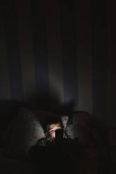 Kleiner Junge, der nachts im Bett sein Smartphone benutzt - LJF01076