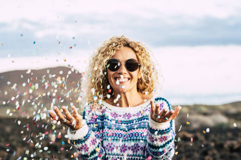 Portrait of happy blond woman celebrating with confetti, Tenerife, Spain stock photo