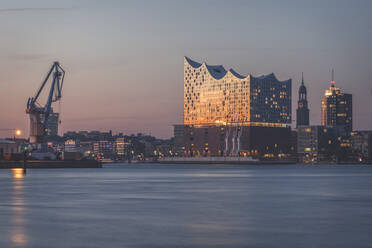 Deutschland, Hamburg, Industriekran und Elbphilharmonie in der Abenddämmerung - KEBF01451