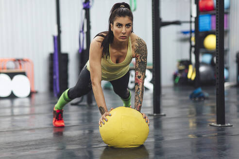 Sportler macht Liegestütze mit Medizinball im Fitnessstudio - CAVF70416