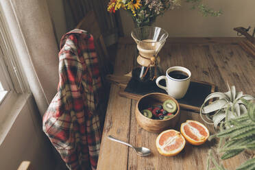 Hohe Winkel Ansicht der Früchte mit Kaffee und Topfpflanze auf Holztisch - CAVF70425