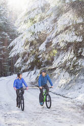 Paar beim Mountainbiken im Schnee - HOXF04420