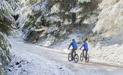 Couple mountain biking in snowy woods - HOXF04423