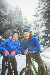 Porträtpaar beim Mountainbiking im Schnee - HOXF04426