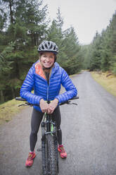 Porträt lächelnde Frau beim Mountainbiking - HOXF04435