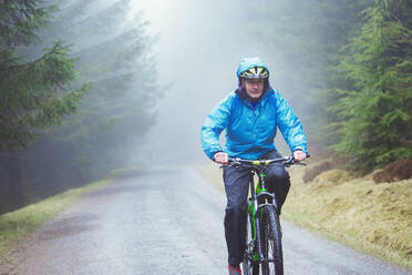 Älterer Mann beim Mountainbiking im Wald - HOXF04438