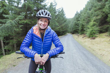 Portrait smiling woman mountain biking - HOXF04439