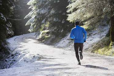 Mann joggt im verschneiten Wald - HOXF04465