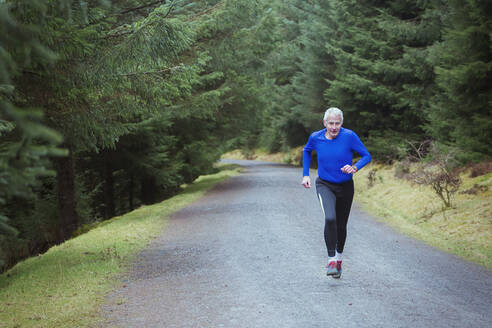 Älterer Mann joggt im Wald - HOXF04470