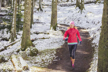 Woman jogging in snowy woods - HOXF04479