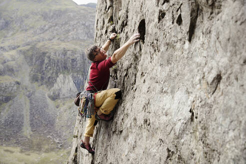 Fokussierter männlicher Kletterer beim Erklimmen einer Felswand - HOXF04485