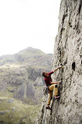 Männlicher Bergsteiger beim Erklimmen einer Felswand, Blick nach oben - HOXF04487