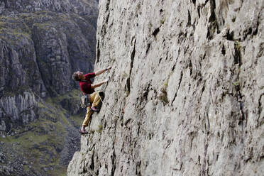 Männlicher Bergsteiger beim Erklimmen einer Felswand, Blick nach oben - HOXF04488