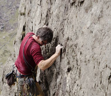 Männlicher Kletterer beim Erklimmen einer Felswand - HOXF04489