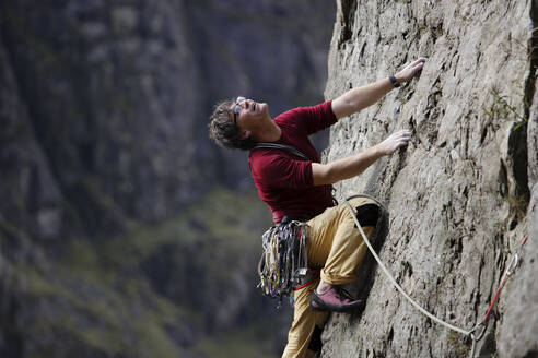 Männlicher Bergsteiger beim Erklimmen einer Felswand, Blick nach oben - HOXF04491