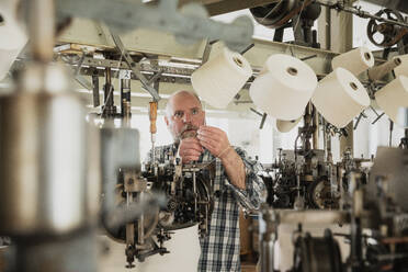 Arbeiter, der eine Rundstrickmaschine einstellt, Garn einfädelt - SDAHF00026