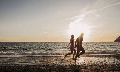 Junges Paar läuft bei Sonnenuntergang am Strand - LJF01091