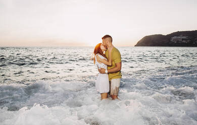 Young couple kissing each other at the beach during sunset - LJF01096