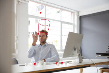 Young businessman in his office, throwing a ball in a hoop - MOEF02695