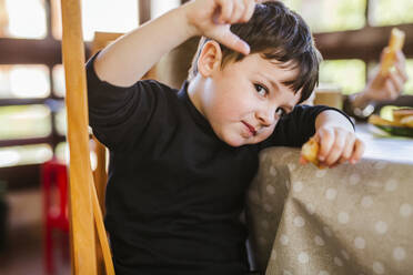 Porträt eines Jungen, der zu Hause am Tisch Churros isst - LJF01104