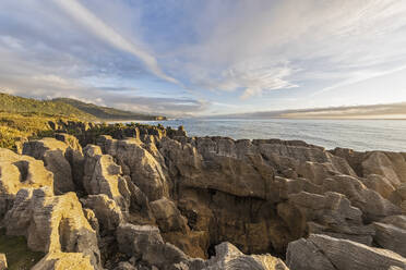 New Zealand, Buller District, Punakaiki, Limestone Pancake Rocks formation and coastal blow hole at dusk - FOF11394