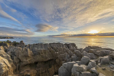 New Zealand, Buller District, Punakaiki, Limestone Pancake Rocks formation and coastal blow hole at sunset - FOF11398
