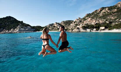 Junges Paar, das von einer Jacht ins Meer springt, Insel La Maddalena, Sardinien, Italien - CUF53537